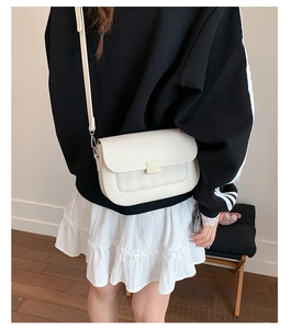 Gros plan d'un sac bandoulière blanc avec panneau à carreaux et fermoir mat