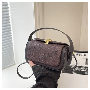 Close-up of deep brown vintage box bag featuring 3D floral embossing and metal clasp