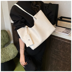 Détail du sac cabas blanc tissé avec pochette assortie porté par un mannequin