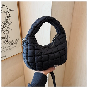 Close-up of black quilted puffer handbag with padded handle and textured fiber detail