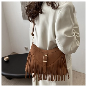 Detail of bohemian brown suede tote bag with long tassels and stylish metal buckle closure