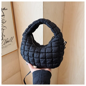 Close-up of black quilted puffer bag featuring a soft texture and top handle detail