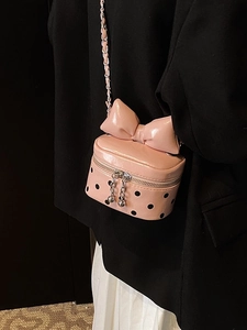 Pink mini crossbody bag with black polka dots and large bow detail on chain strap