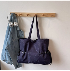 Détail du cabas violet à motif marbre avec poches à cordon et plaque métallique élégante