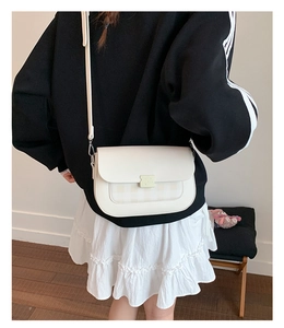 Détail d'un sac à bandoulière blanc cassé montrant le rabat élégant et le motif