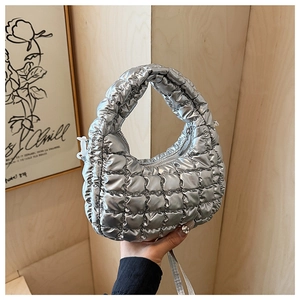 Close-up of a silver quilted puffer shoulder bag with metallic finish and top zipper