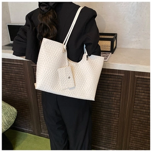 Vue détaillée du sac cabas en cuir tressé blanc avec une mini pochette sur bois