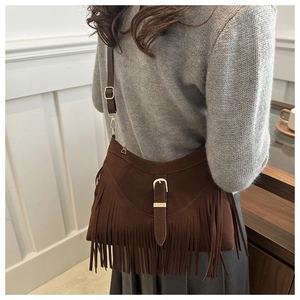 Detalle del bolso con flecos de ante marrón oscuro con hebilla metálica y estilo boho