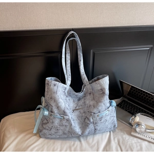 Détail du sac cabas à motif marbre avec nœud latéral et poches de rangement avant