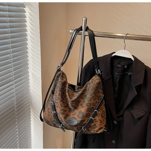 Detail view of leopard print hobo bag with sleek black straps and round logo patch