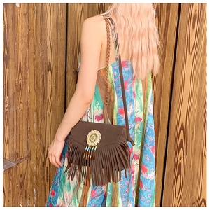 Détail d'un sac bohème en daim marron avec franges colorées et ornements tissés ronds
