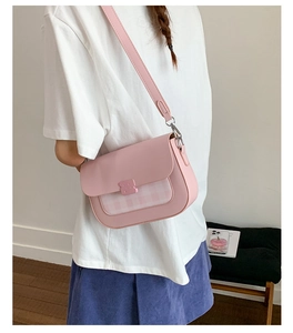 Sac bandoulière rose avec motif à carreaux et boucle d'ours porté par un mannequin