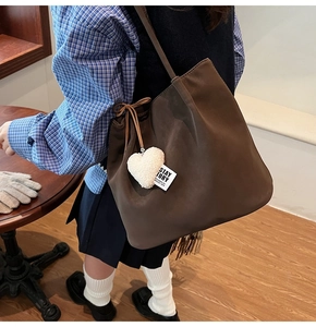 Detail of dark brown matte tote bag featuring a soft white fleece heart charm