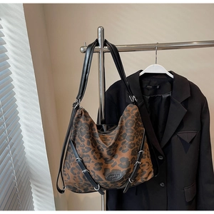 Detailed close-up of leopard print tote bag with black leather straps and brand patch