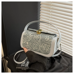 Detail of vintage grey leather box bag showing embossed floral pattern and gold clasp