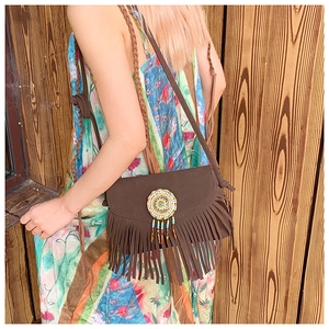 Détail du sac bandoulière en daim marron avec franges et motif en perles colorées