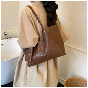 Détail du sac cabas marron foncé avec texture en cuir tressé et coupe asymétrique en L