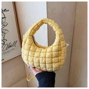Detail of yellow quilted cloud bag with padded texture and slim shoulder strap