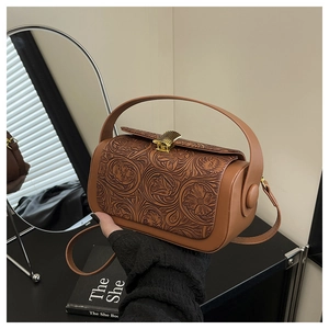 Close-up of brown floral embossed leather bag with golden metal clasp and strap