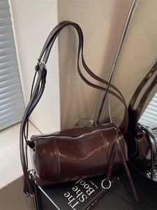 Polished chocolate brown cylinder shoulder bag with leather tassels and adjustable strap