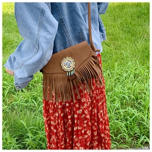 Détail d'un sac bandoulière bohème en daim marron avec franges et broderie de perles colorées