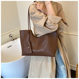 Détails de texture tressée sur un cabas marron foncé avec petite pochette assortie