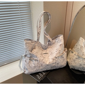Gros plan d'un grand sac fourre-tout avec texture marbre blanc et poches latérales à cordon