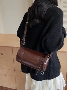 Deep brown cylindrical crossbody bag with adjustable strap and sleek silver hardware