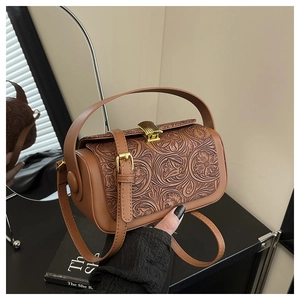 Detailed view of floral embossed leather handbag with vintage golden shell clasp and strap