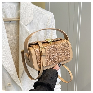 Detail of floral embossed leather handbag with golden lock in milk tea color