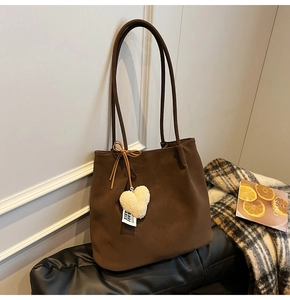Close-up of matte dark brown tote bag with suede texture and plush heart charm detail