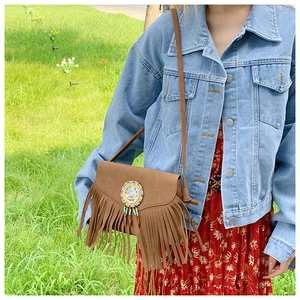 Détail d'un sac à bandoulière marron en daim avec franges et perles de style bohème