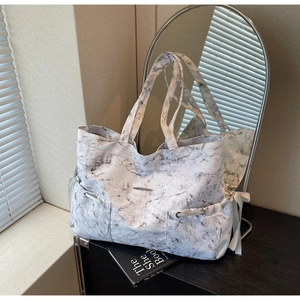 Détail du sac cabas à motif marbre avec nœuds de serrage latéraux et accent métal