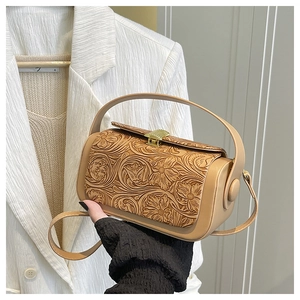 Detail of light beige vintage box bag featuring floral embossing and gold retro buckle