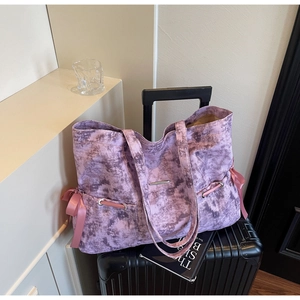 Détail d'un sac cabas en toile marbrée violette avec ruban rose et œillet métallique