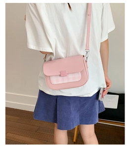 Détail du sac bandoulière à carreaux rose avec boucle carrée dans un cadre chaleureux