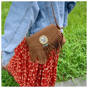 Détail du sac en daim marron avec franges et ornement de perles au style bohème vintage