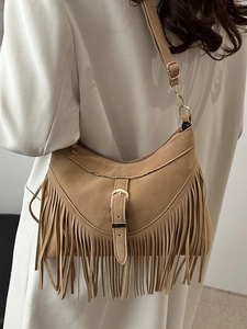 Bohemian tan suede crossbody bag with fringe details and gold buckle displayed on model