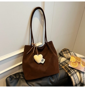 Close-up of a coffee brown matte tote bag featuring a plush white heart pendant