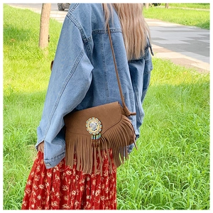 Détail d'un sac bandoulière en daim marron avec franges et perles de style bohème