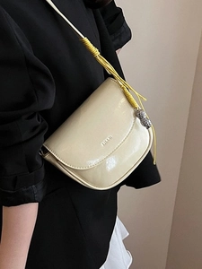 Sacoche selle beige chic avec bandoulière tissée et pendentif cacahuète sur mannequin