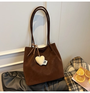 Detail of dark brown faux suede tote bag with a plush heart charm and slim straps