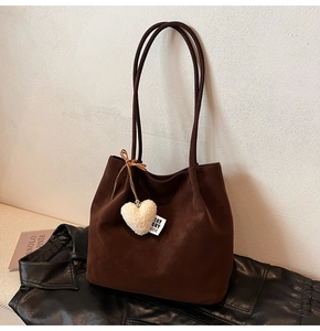 Detail of dark brown matte tote bag with white heart plush pendant and shoulder strap