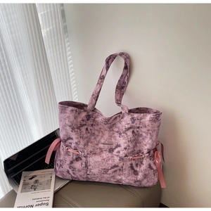 Détail du sac cabas en toile tie-dye rose avec nœuds en ruban et poches frontales