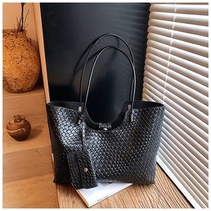 Détail du sac cabas tressé noir avec pochette zippée assortie dans un décor minimaliste