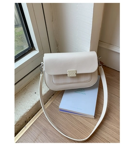 Détail d'un sac à bandoulière rectangulaire blanc crème avec fermoir en forme de fromage