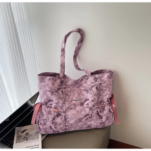 Détail du cabas en toile tie-dye violette avec nœuds latéraux en satin rose