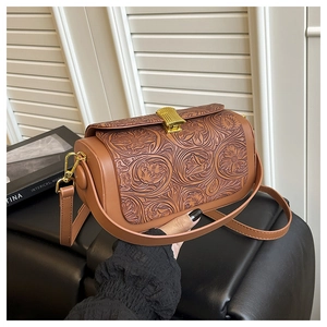 Detailed close-up of brown leather handbag featuring embossed floral pattern and vintage gold clasp