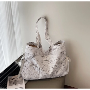 Détail du sac cabas en toile avec motif marbré et ruban de serrage latéral décoratif