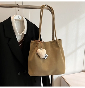 Detail of khaki faux suede tote bag with white heart plush pendant and brand label
